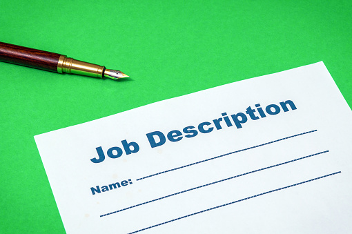 Job Description with Pen before writing on green background or desk