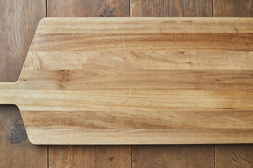 Background texture of an empty rustic cutting board on a wooden kitchen table, background ideal for product placement, with a large copy space area