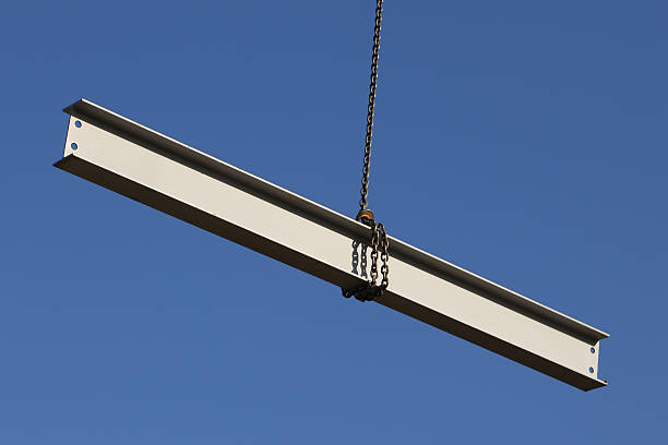Steel girder wrapped in a giant hanging in the air Steel girder swinging from a crane on a construction site girder photos stock pictures, royalty-free photos & images
