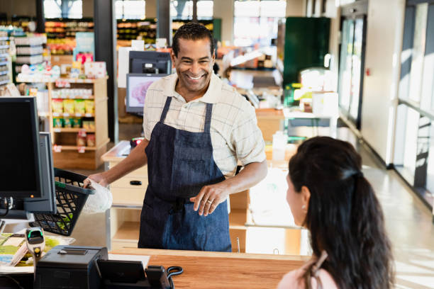 istock Friendly grocery store owner greets female customer at checkout 1451848890