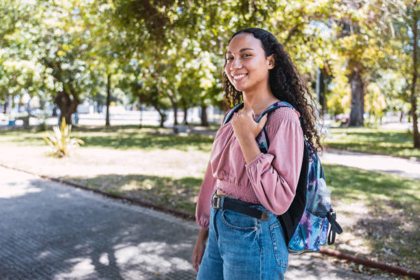 mulher estudante latina jovem feliz em pé no parque. autoconfiança saudável. geração z - african ethnicity standing college student curly hair - fotografias e filmes do acervo