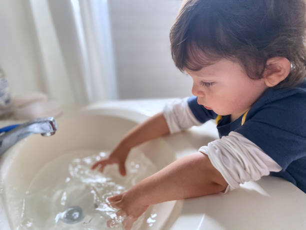 istock Toddler playing with water in sink 1451854440