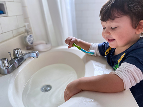 View of boy brushing teeth at home in a bathroom