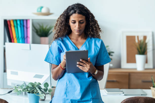 istock Female nurse using her digital tablet while standing in the consultation. 1451854860