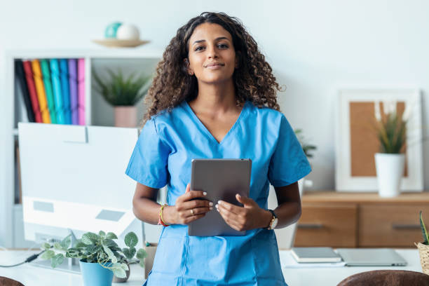 Female nurse using her digital tablet while standing in the consultation.