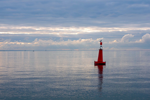 Seagull sits on a buoy in the sunset sea, sea horizon. Buoy with seagull sitting on top