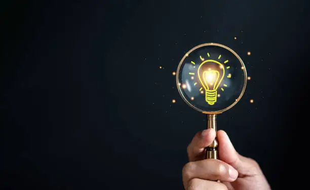 Photo of Magnifying glass focus to light bulb icon which for mind, creative, idea, innovation, motivation planning development leadership and customer target group concept.