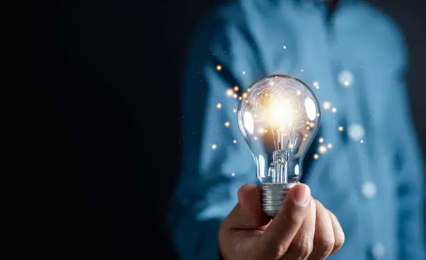 Photo of Innovation through ideas and inspiration ideas. Human hand holding light bulb to illuminate, idea of creativity and inspiration concept of sustainable business development.