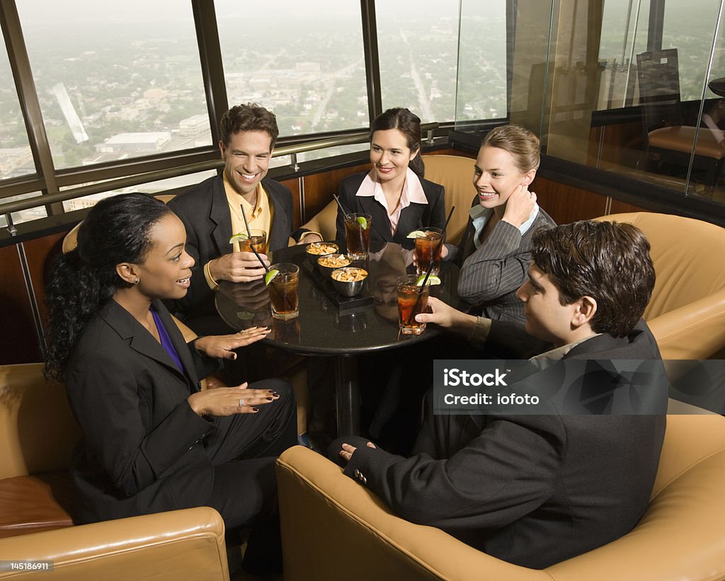 Business people eating. Ethnically diverse businesspeople sitting at table in restaurant talking. Discussion Stock Photo