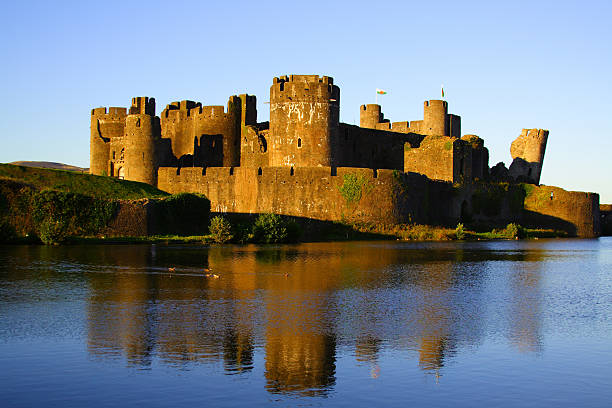 istock Golden lit Caerphilly castle with reflection in blue water 145187139