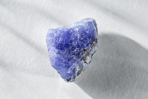 Rough Uncut Blue and Violet Tanzanite Gem on White Background. Tanzanite is the most Valuable Gemstone