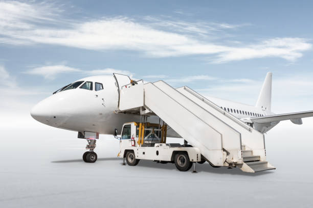 istock White passenger airliner with a boarding stairs isolated on bright background with sky 1451871871