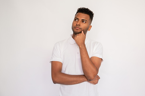 Portrait of a good looking young man looking up and thinking hard against a white background
