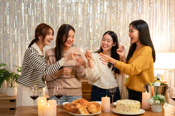 Young beautiful woman holding sparkler lights firework with enjoying in night while dinner to celebrating in new year party festive at home