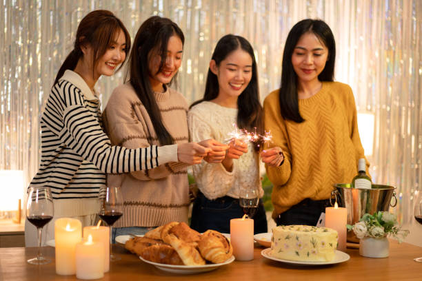 istock Young beautiful woman holding sparkler lights firework with enjoying in night while dinner to celebrating in new year party festive at home 1451873641