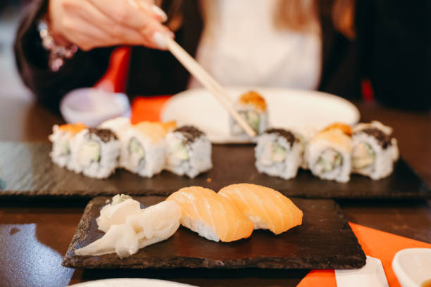 istock Young woman eating sushi rolls 1451878591