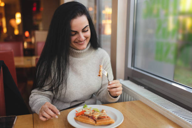 istock Beautiful young woman eating pizza in a restaurant while on a lunch break 1451885837
