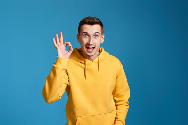 istock young man in yellow sweatshirt showing Ok gesture 1451892301