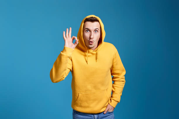 istock young man in yellow sweatshirt showing Ok gesture 1451892353