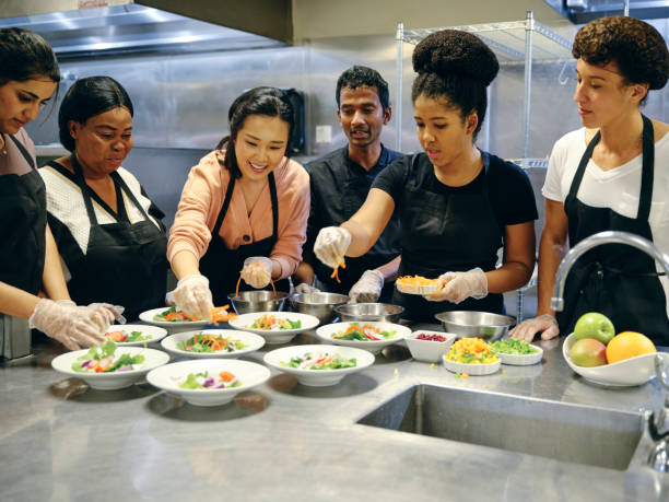 Culinary Students in a Commercial Kitchen A restaurant insurance cover teaching chef works with a group of students in a commercial kitchen. restaurant workers stock pictures, medical costs royalty-free photos & images