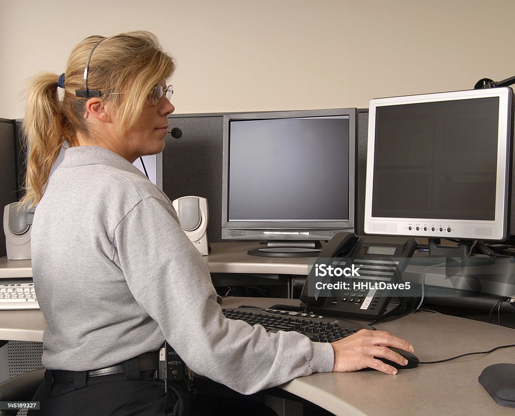 Police dispatcher working at console A police dispatcher working at console Emergency Services Occupation Stock Photo