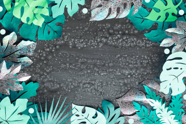 istock Frame made from exotic paper leaves. Paper craft background, tropical leaves with text space on dark textured background. Copy-space framed with layered floral elements. 1451896848