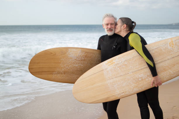 istock Happy elderly couple going in for surfing together 1451899302