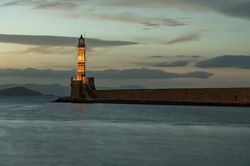 Crete's lighthouse in the center of a sea beneath the clouded sky of Greece's sunset
