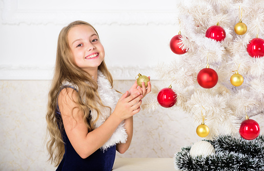 Kid cheerful excited about new year coming. Family holiday concept. Small girl wear velvet dress feels festive near christmas tree. Christmas very special time of year. Spread christmas cheer.