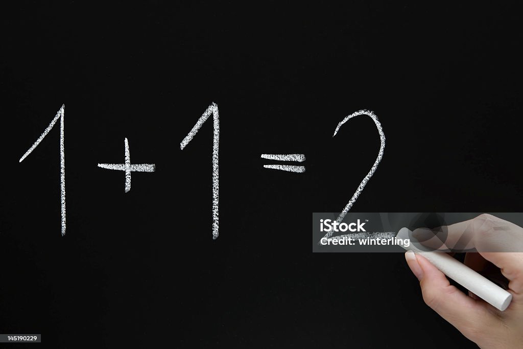 Basic Calculations Female teacher writing on a chalkboard. Adult Stock Photo