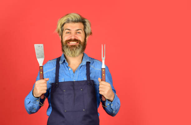 Bbq food. Cooking utensils. Summer picnic. Bbq american tradition. Culinary concept. Tools roasting meat. Man in apron hold barbecue grill. Hipster dyed beard promoting bbq equipment. Cooking healthy