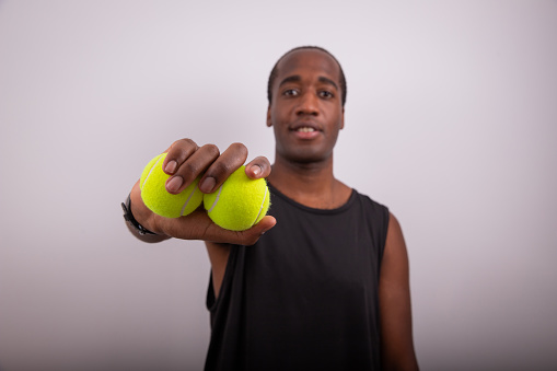 A sportsman with two tennis balls, advertising photo in the studio with a white background and copy space