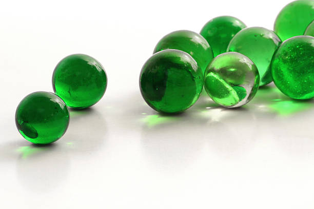 A group of green glass marbles on a white background.