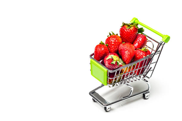 Strawberries in a shopping cart as conceptual image.Miniature shopping cart with strawberries on white background