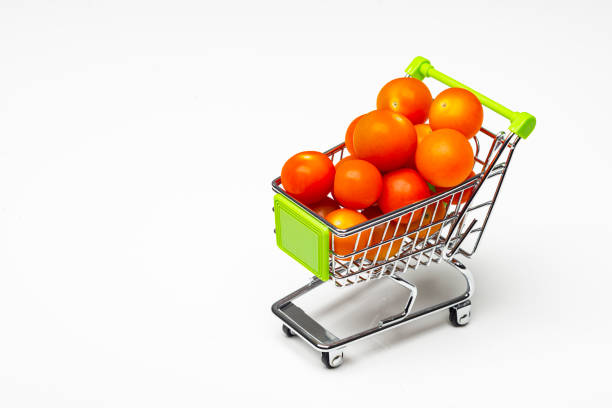 Fresh cherry tomatoes in a miniature shopping cart as conceptual image.Miniature shopping cart with cherry tomatoes on white background