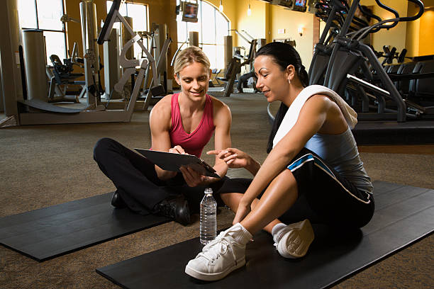 Adult female with personal trainer at gym. stock photo