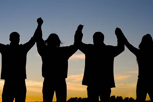 Silhouette image of happy family making high hands in sunset