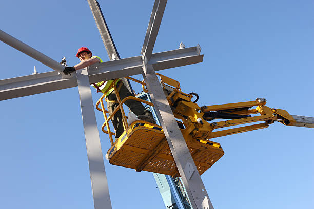 Steel Erector Steel worker assembling the framework of a new building from a cherry-picker erection stock pictures, royalty-free photos & images