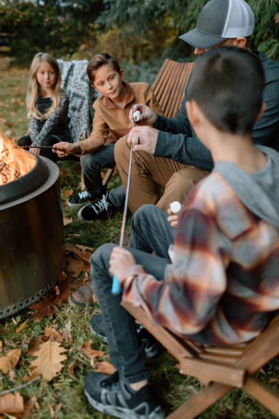 istock Dad helping kids roast marshmallows around fire 1451935212