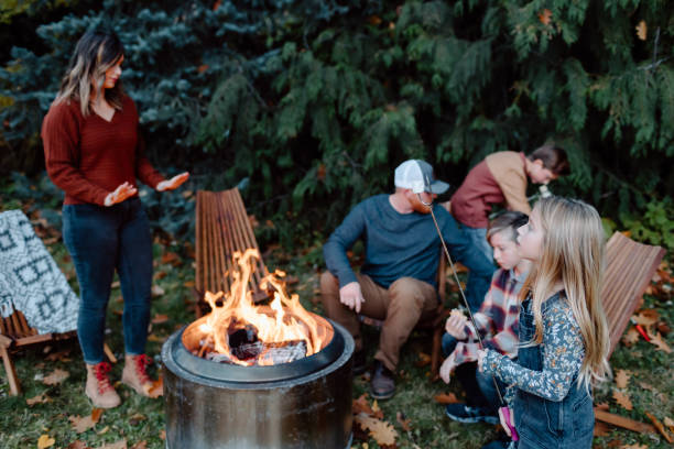 Family roasting marshmallows around fire A family with elementary age children gathers around a fire pit in the backyard and roasts marshmallows. smore photos stock pictures, royalty-free photos & images