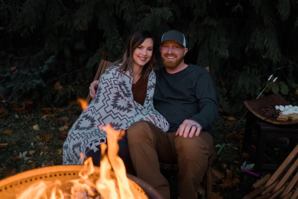 istock Husband and wife relaxing next to a fire outside 1451935265