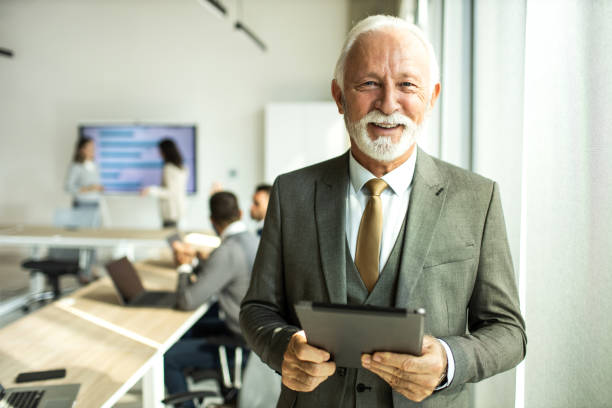 Confident senior man businessman working inside modern office on a digital tablet stock photo
