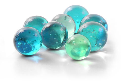 A handful of bright turquoise marbles of varying shades on a white background.