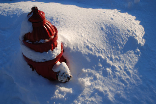 Red Fire Hydrant buried in a deep winter snowfall.