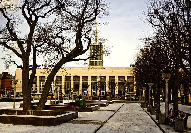 Finlyandski railwaystation in winter time. Building in Sankt-Petersburg with turret and clock. Facing railway station is square with trees, lanterns, benches and quadratic fountain pans.