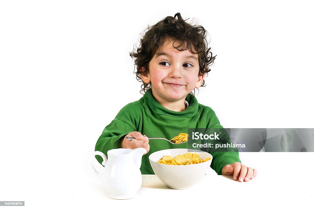 Young boy with a green sweatshirt, eating cornflakes young boy eating cornflakes isolated on white Child Stock Photo