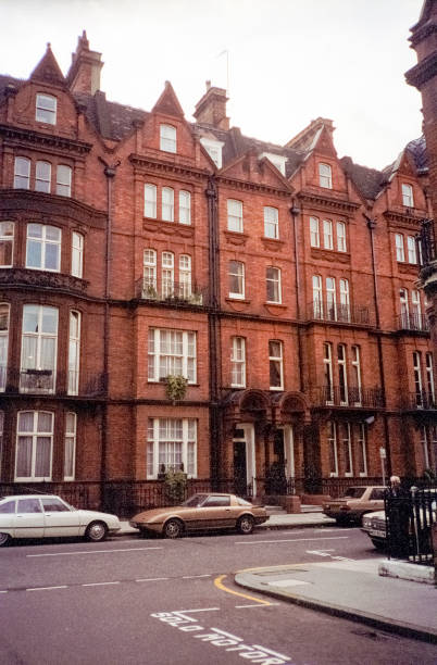 London, England- 1983: A vintage 1980's Nikon negative film scan of the streets of Mayfair, London with distinct architectural buildings and cars parked on the road.