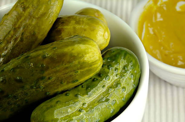 Pickled Cucumbers in a White Dish Pickled cucumbers arranged in a white dish with mustard. dill pickle stock pictures, royalty-free photos & images