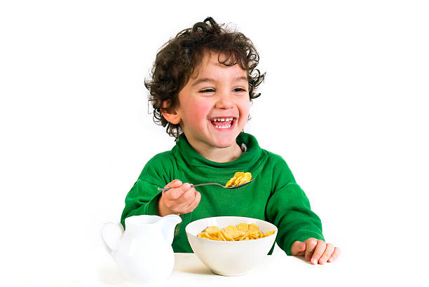 istock Young boy laughing, enjoying his morning cereal with milk 145198460