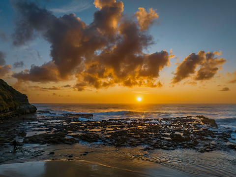 Aerial sunrise seascape with clouds,  rock platform, good size waves and plenty of atmosphere at North Avoca Beach on the Central Coast, NSW, Australia.